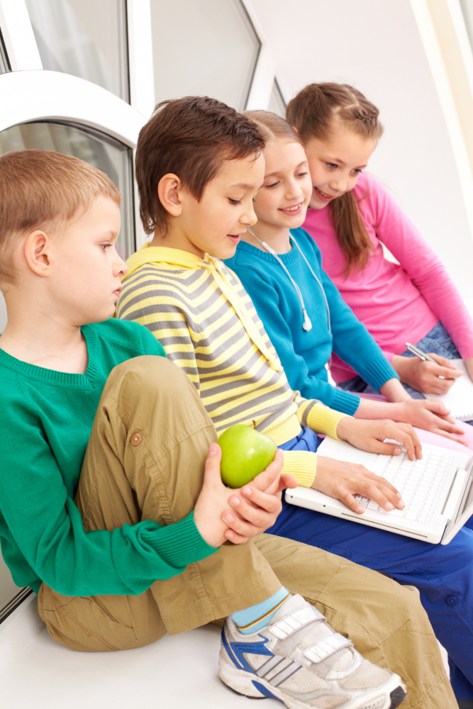 Four children sitting together looking at a laptop
