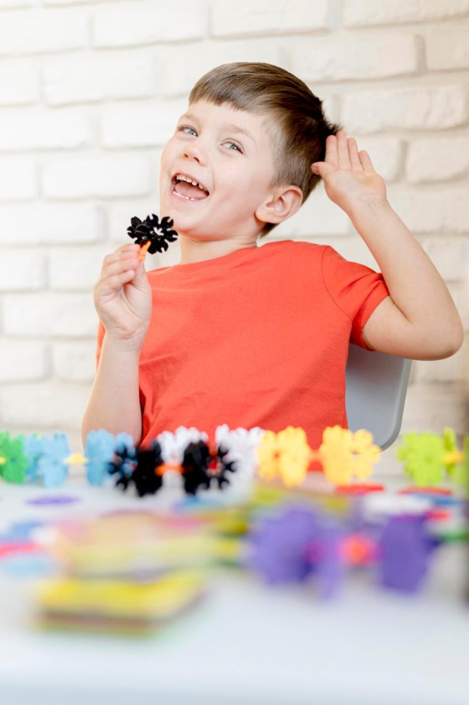 A smiling boy playing with colourful building pieces at a table